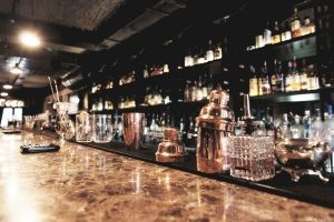 glass bottles lined up in a bar with nightlife insurance to protect themselves against customer altercations