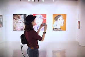 a woman taking pictures at an art exhibit that has special event insurance since there are very large sculptures