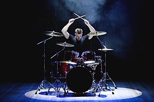 a rock drummer at a live show in front of thousands of people and therefore is covered by band insurance in case something were to happen during his performance