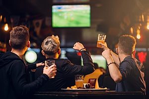 three friends watching soccer at a bar that has protections against liquor liability