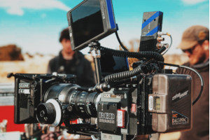 a black digital video camera mounted on a tripod on a film production set that has film production insurance