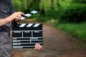 a man holding a clapperboard on the set of a short term film production that is covered by insurance
