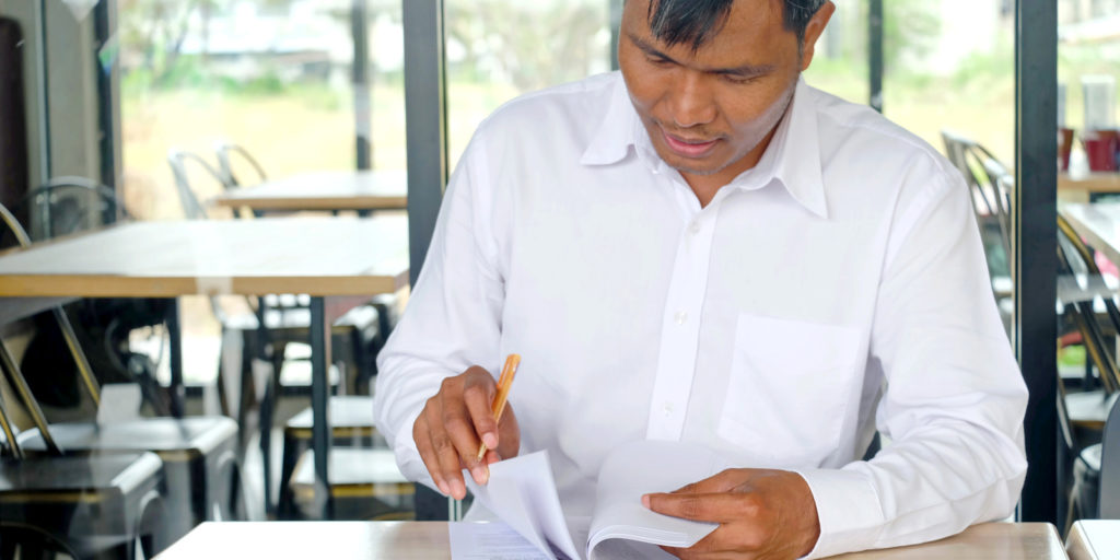 a restaurant owner looking through and signing for restaurant insurance