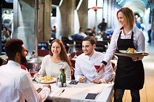 friends and server smiling at a restaurant with insurance