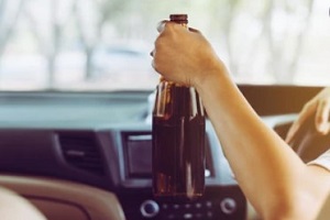man holding liquor bottle in the car