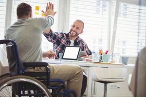 handicap businessman giving high five to colleague in creative office
