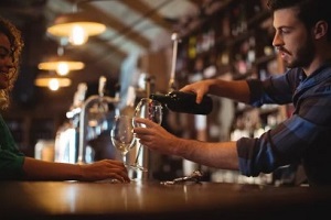 bartender pouring wine in glass in a bar protected with wine bar insurance