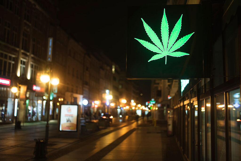 neon sign of a cannabis leaf on a busy street