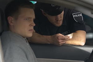 police officer checking a young man license in a car