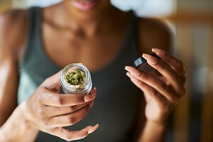 african american woman opening bottle of legal marijuana from dispensary close up