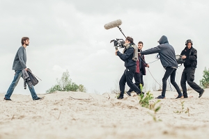 film crew filming a scene of star walking in desert