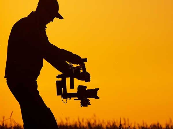 Videographer filming a movie at sunset