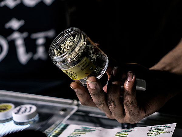 close up of hand holding cannabis jar