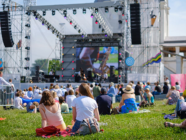 group of people sitting on the lawn of a festival