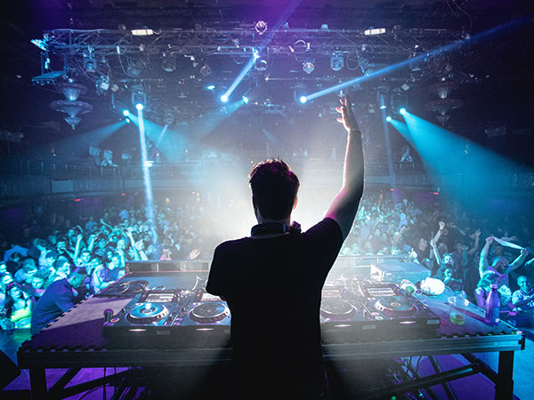 silhouette of dj in nightclub and large crowd in front