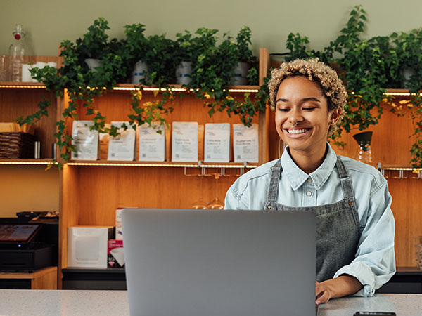 young woman at the front on local store on laptop