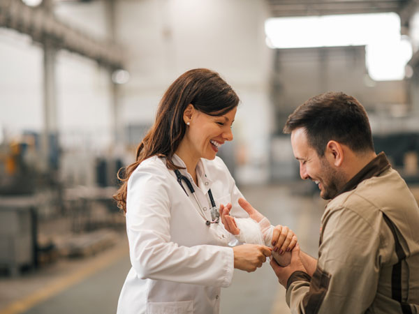 Doctor helping worker who is protected by his company's workers' compensation insurance policy