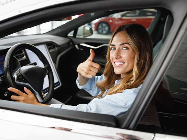 Woman at work giving thumbs up in company car