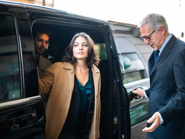 Woman exiting hotel transportation vehicle which is protected by hospitality commercial auto insurance