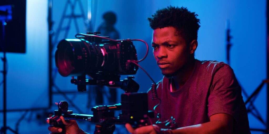 african american camera operator shooting on professional camera in dark studio
