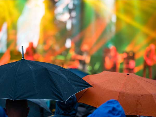 Concert goers holding umbrellas in the rain