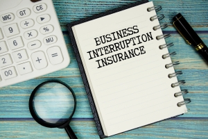 Business Interruption Insurance Text on Notepad with Magnifying Glass