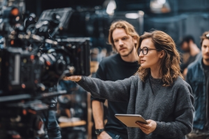Woman with Digital Tablet Operating Professional Video Camera on Film Set