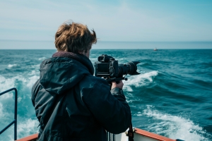 Filmmaker on A Boat with Video Camera in Hand