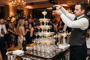 Waiter Pouring Champagne Into Pyramid Glasses at Party
